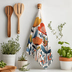 Mediterranean botanical tea towel displayed over an oven handle with vibrant floral design and neutral cream background.