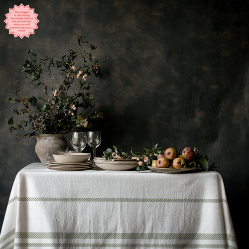Sage green striped tablecloth creating an elegant European-inspired tablescape with white ceramics and natural décor.