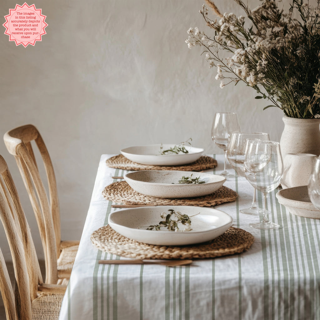 French Riviera inspired dining table featuring a sage stripe tablecloth, neutral dinnerware, and relaxed Mediterranean styling.