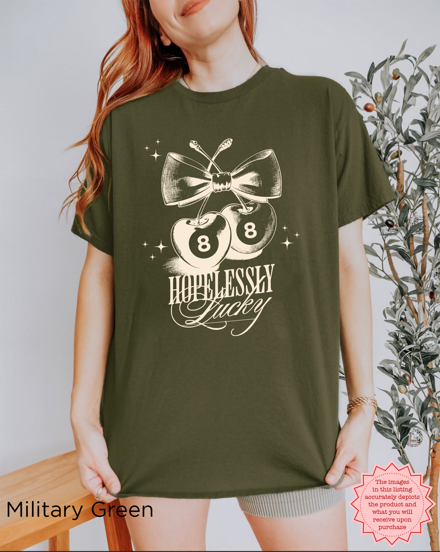 Stylish "Hopelessly Lucky" cherry graphic tee in military green, great for summer fashion.