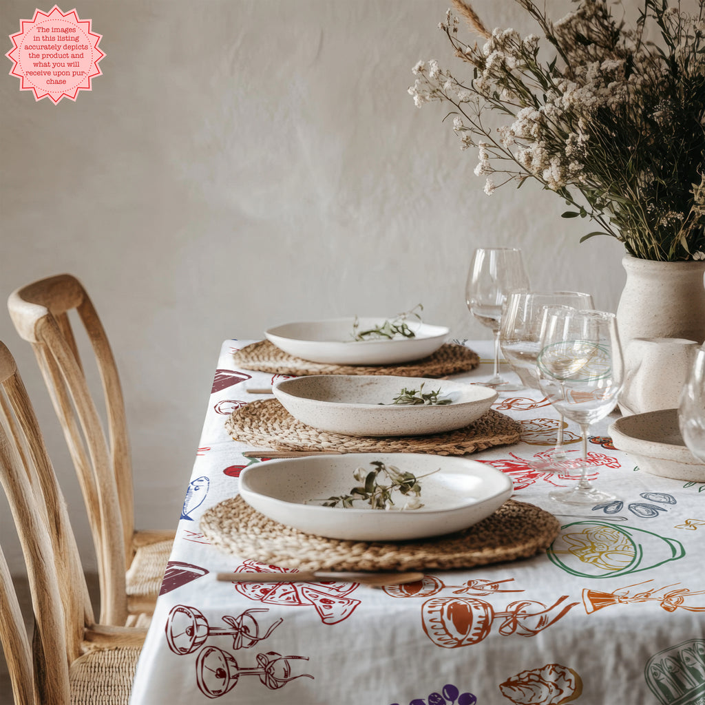 Close-up of Italian Summer Market Tablecloth showing playful illustrated seafood, lemons, pasta, vegetables and Mediterranean kitchen motifs in vibrant colours.