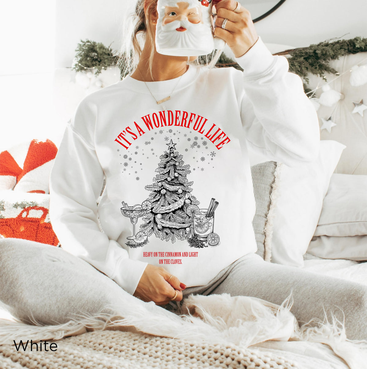 Woman wearing a Cardinal Red Christmas cocktail sweatshirt with festive lounge bottoms in a cosy holiday setting.