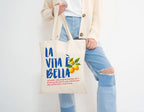 Eco-friendly reusable shopping tote with La Vita è Bella design available in natural and black canvas finishes.