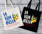 Black cotton canvas tote bag with La Vita è Bella quote and vibrant lemon artwork celebrating Italian lifestyle and Mediterranean living.