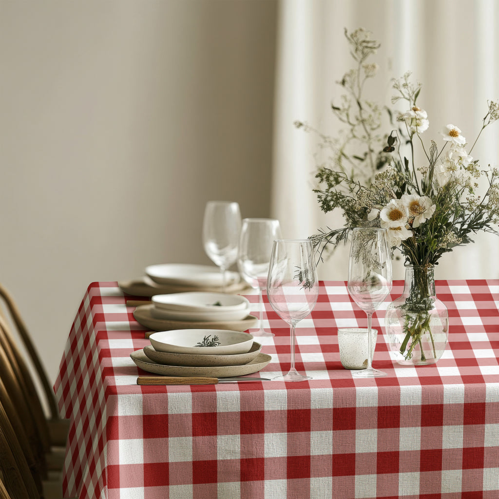 Red gingham cotton tablecloth styled with white dinnerware and festive greenery for Christmas dining.
