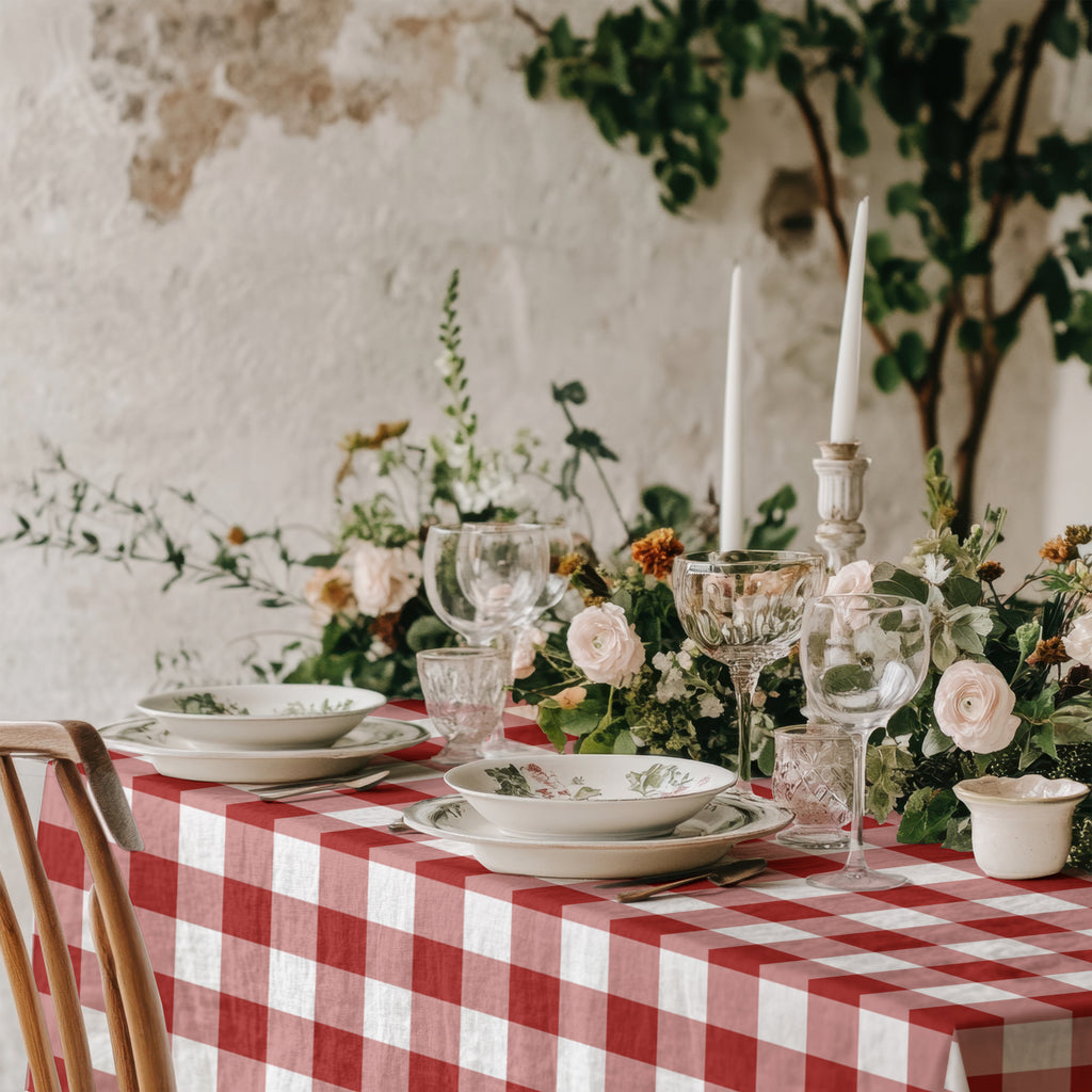 Red gingham cotton tablecloth styled with white dinnerware and festive greenery for Christmas or special celebration dining.