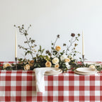 Red gingham table linen styled in a country-inspired dining space with natural textures and simple tableware.