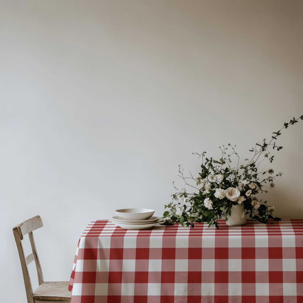 Red gingham cotton twill tablecloth styled on a dining table for a classic and inviting tablescape.