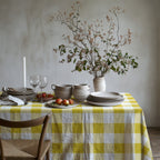 Yellow gingham tablecloth styled with neutral dinnerware and fresh flowers for an elegant everyday tablescape.