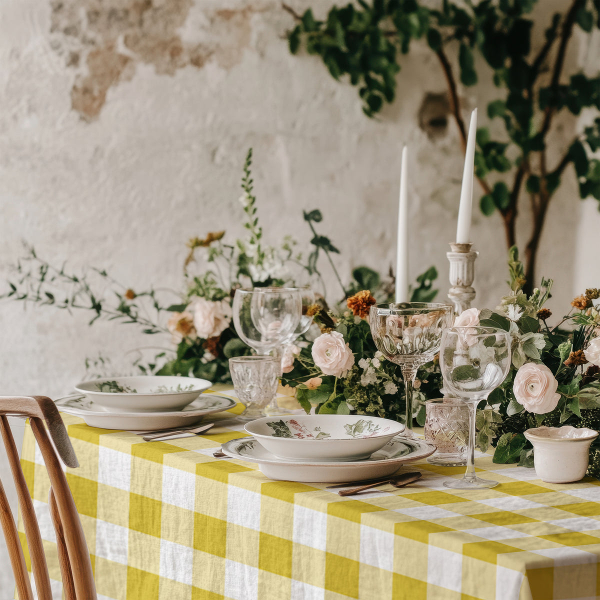 Yellow and white checked cotton tablecloth complementing a special celebration dining room with natural textures and floral decor.