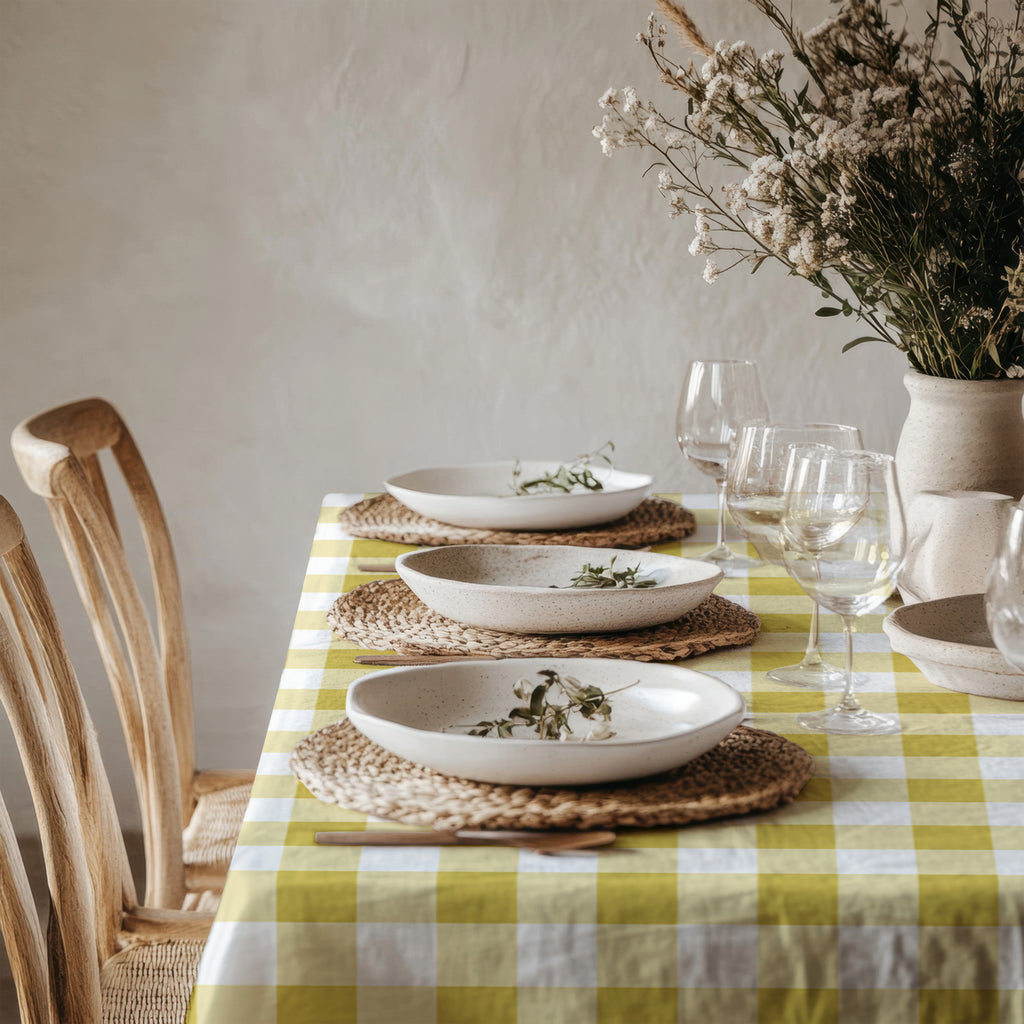 Yellow gingham table linen styled in a charming cottage-inspired dining setting with white ceramics and greenery.