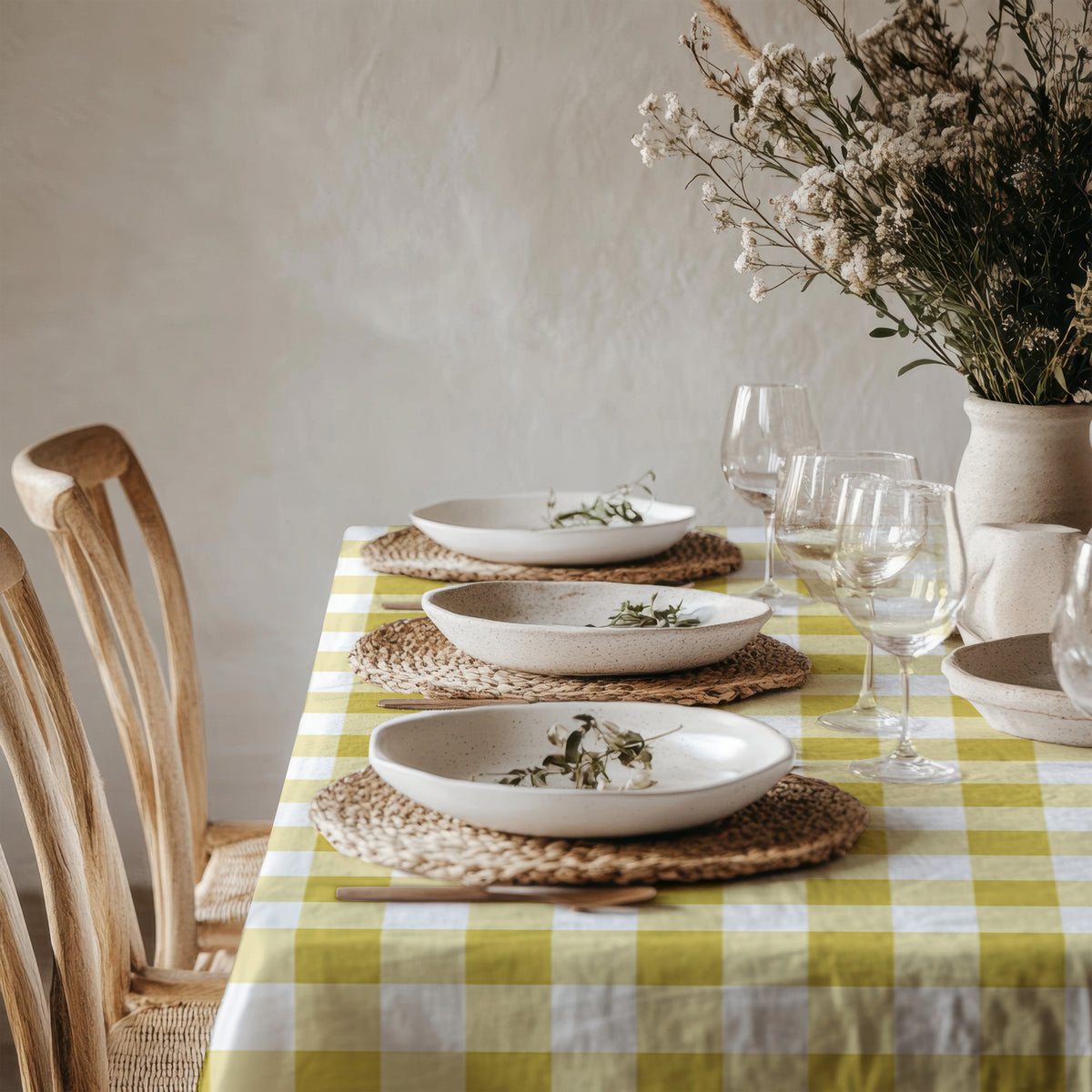 Yellow gingham table linen styled in a charming cottage-inspired dining setting with white ceramics and greenery.