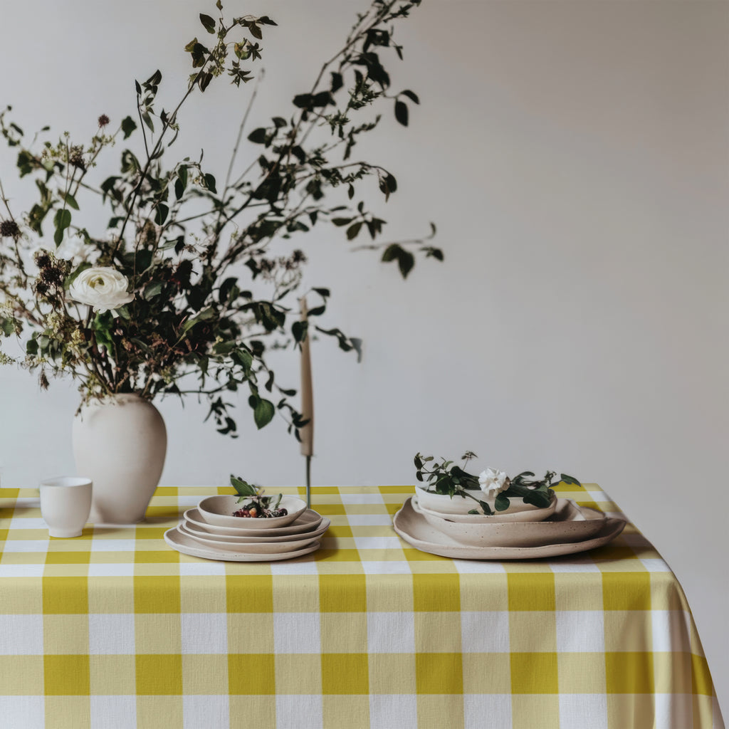 Yellow and white checked cotton tablecloth complementing a neutral dining room with natural textures and simple decor.