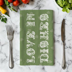 Olive green cotton tea towel with vintage lettering hanging in a Mediterranean style kitchen