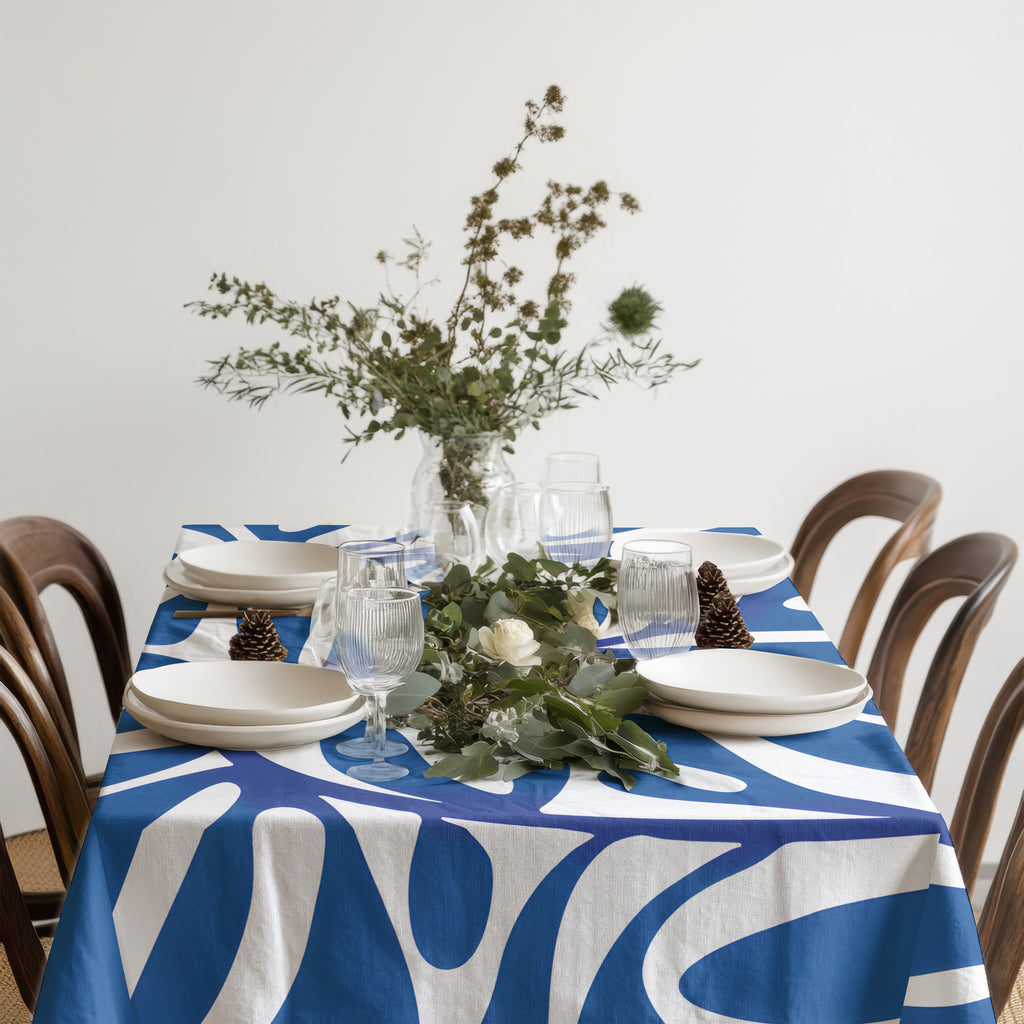 Rectangle blue artistic tablecloth layered with glassware and natural textures