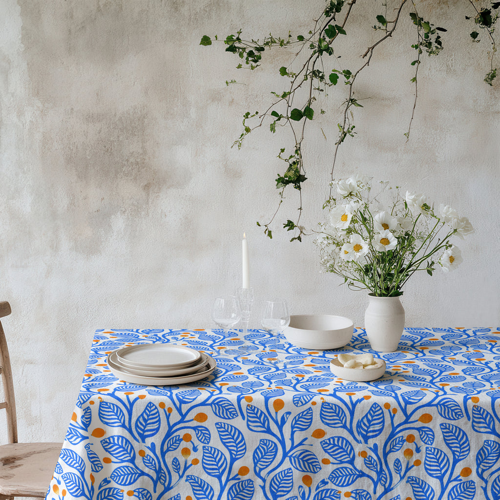 Modern Mediterranean tablecloth with an abstract blue leaf and terracotta botanical pattern on a natural background.