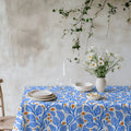 Modern Mediterranean tablecloth with an abstract blue leaf and terracotta botanical pattern on a natural background.