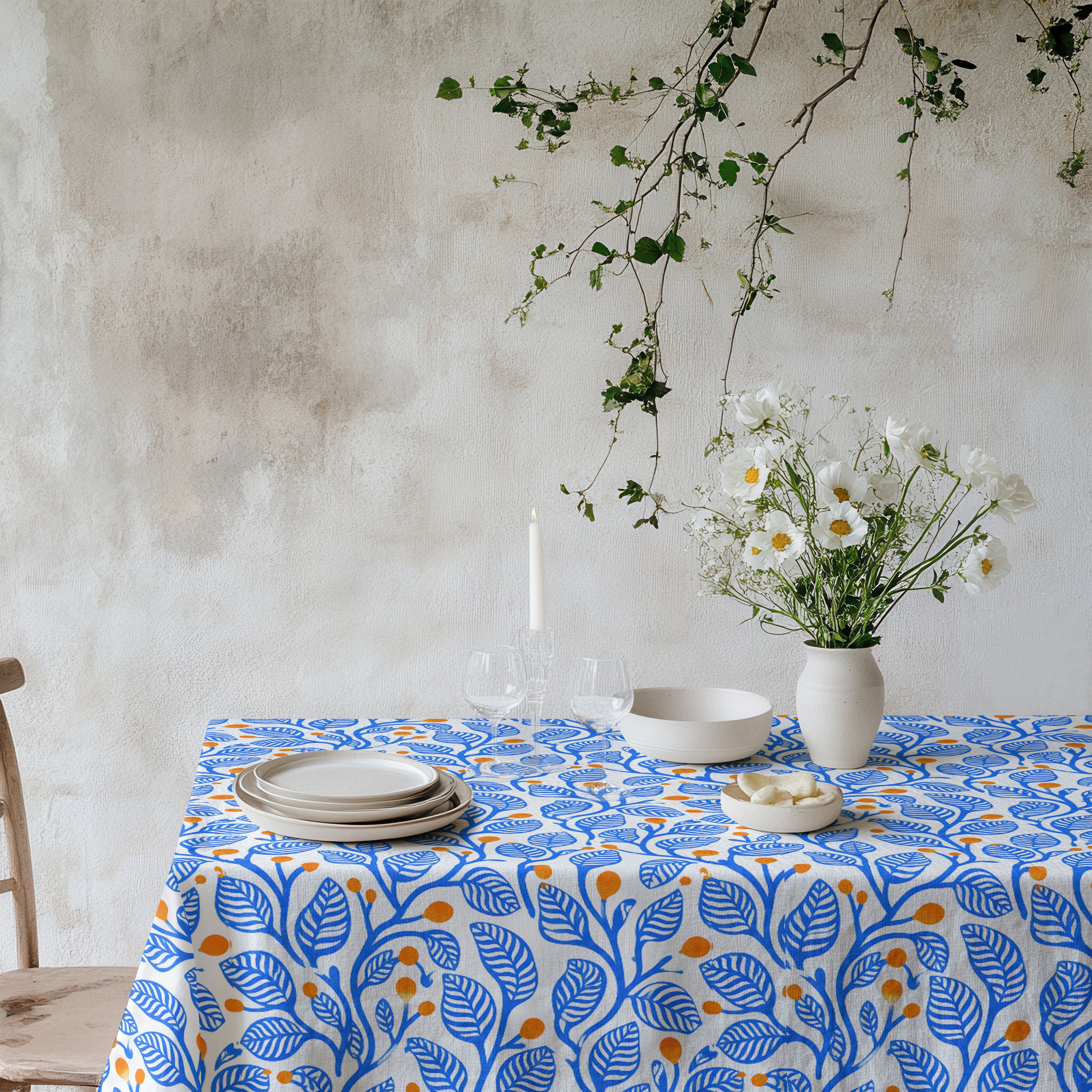 Modern Mediterranean tablecloth with an abstract blue leaf and terracotta botanical pattern on a natural background.