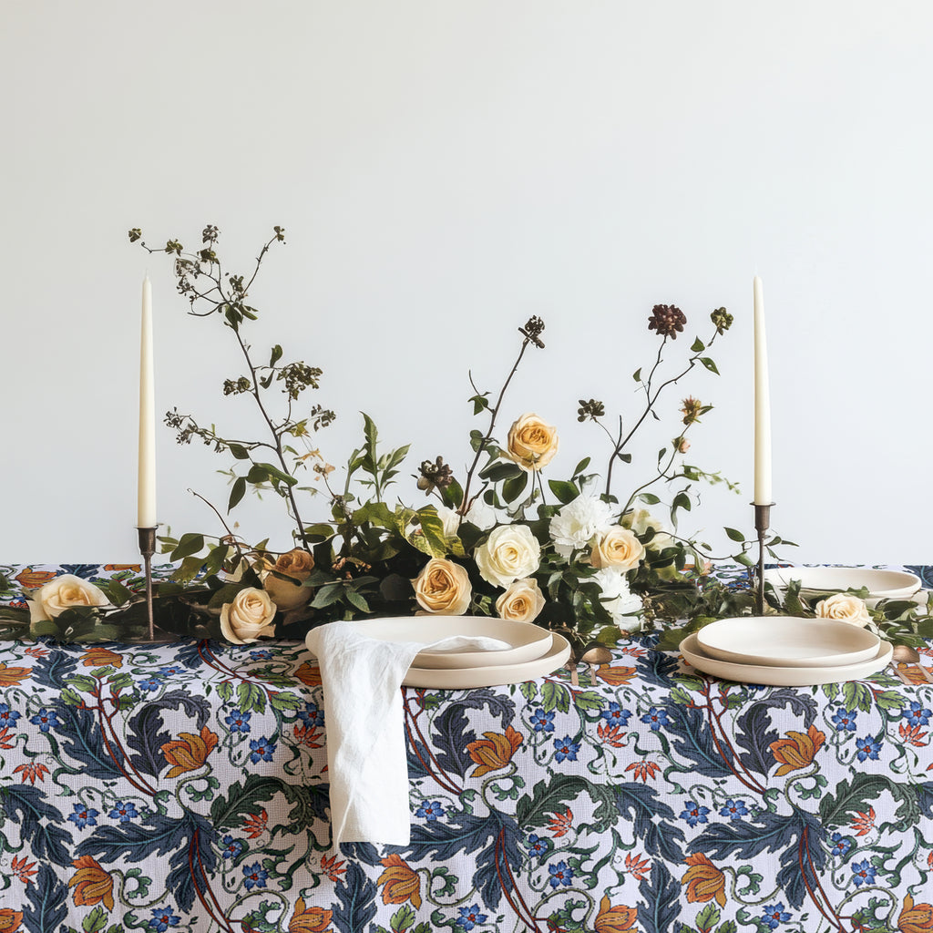 Mediterranean botanical table linen draped over a dining table, showcasing its full floral pattern.