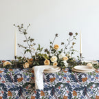Mediterranean botanical table linen draped over a dining table, showcasing its full floral pattern.
