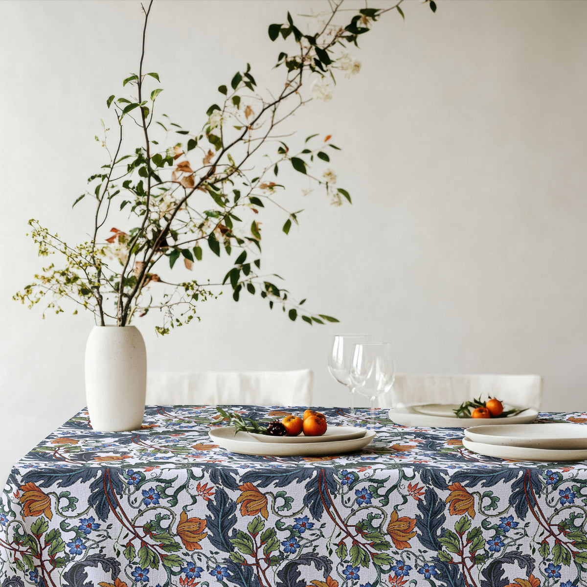 Styled dining setting with Mediterranean floral tablecloth, plates, glassware, and natural decor.