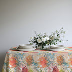 Modern Mediterranean floral tablecloth draped over dining table with simple place settings and fresh greenery