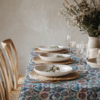 Blue and turquoise Mediterranean floral tablecloth styled with white ceramic dinnerware