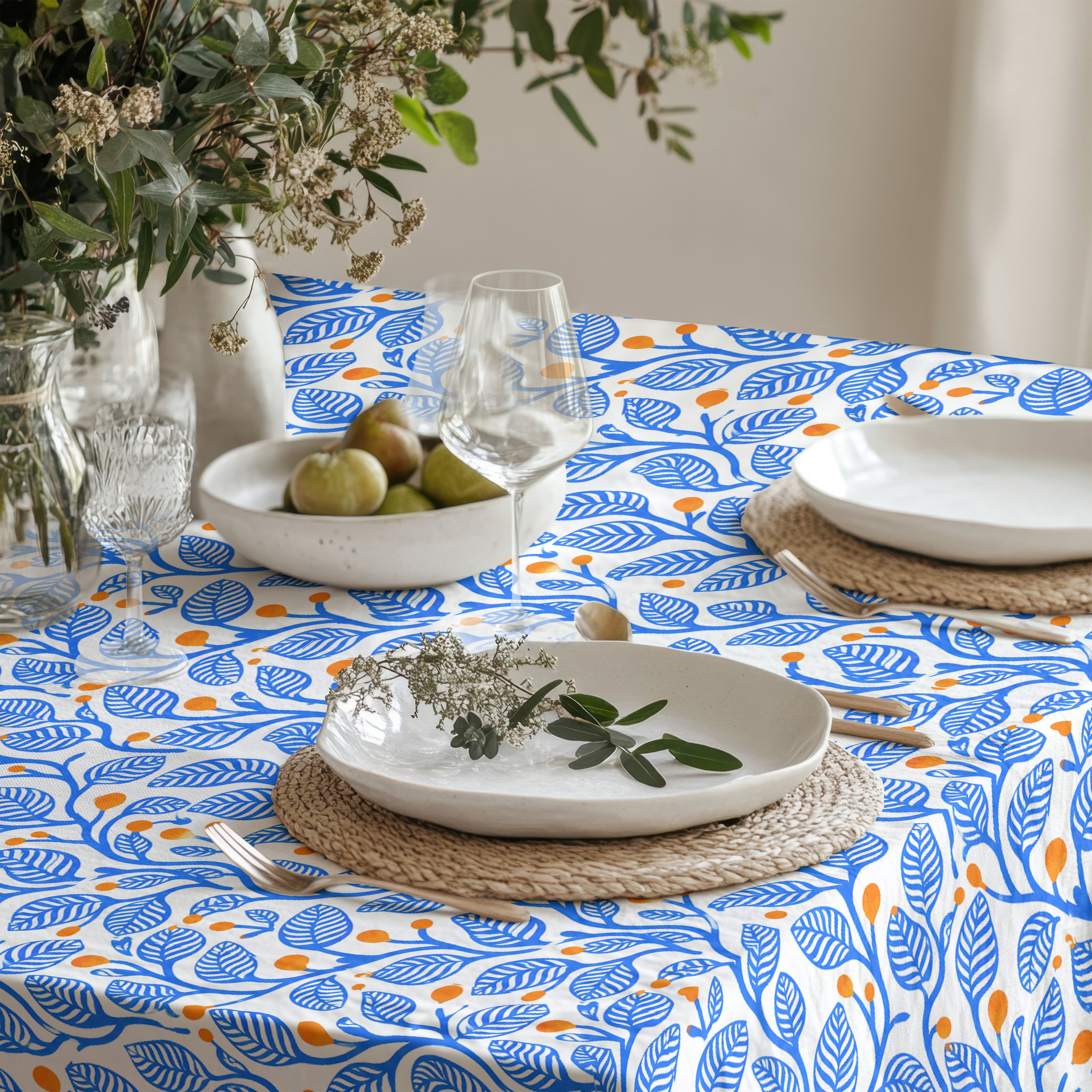 Close-up of the Mediterranean Botanica Tablecloth showcasing flowing blue foliage and terracotta berry motifs on cotton twill fabric.