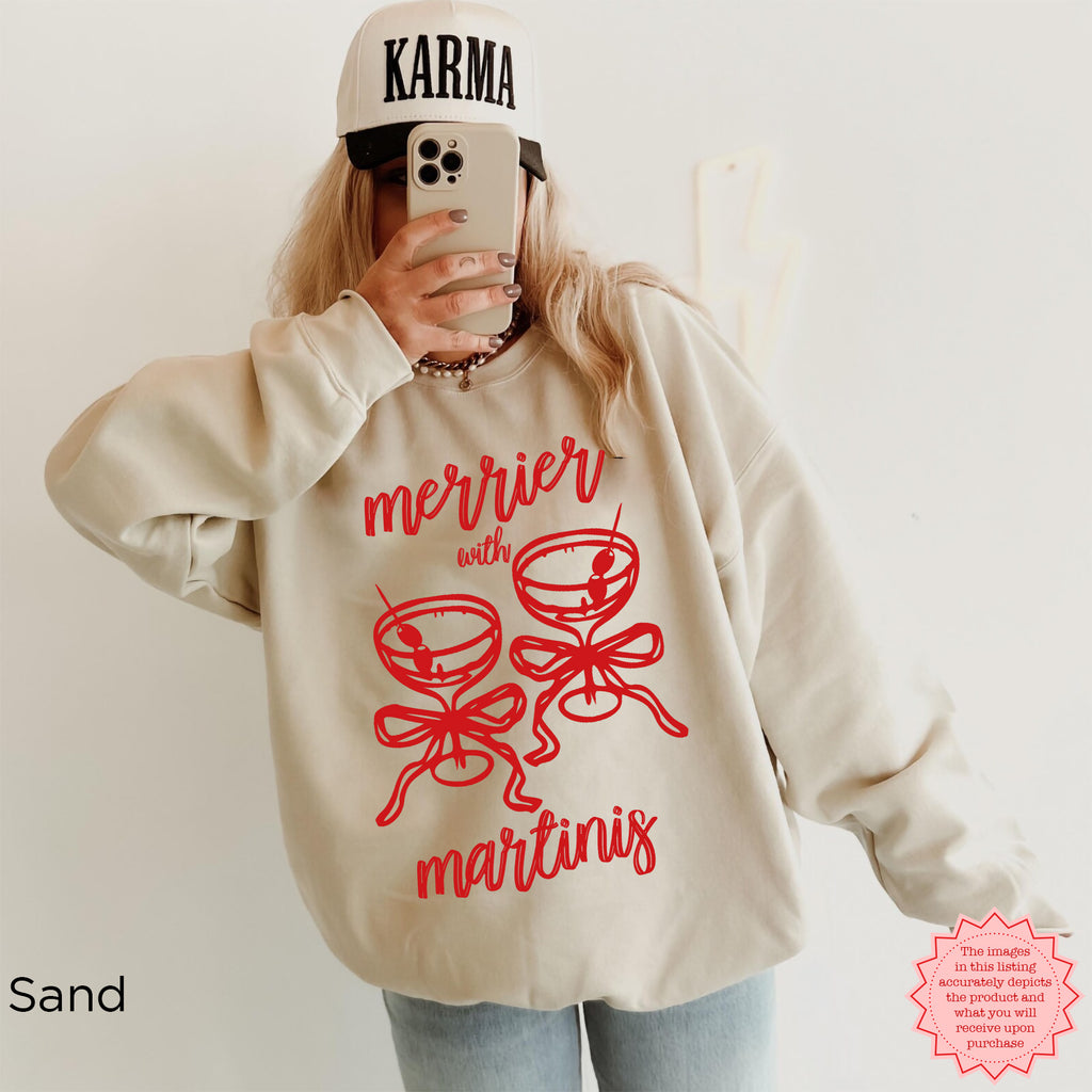 Sand crewneck sweatshirt with “Merrier with a Martini” Christmas cocktail artwork, festive winter apparel.