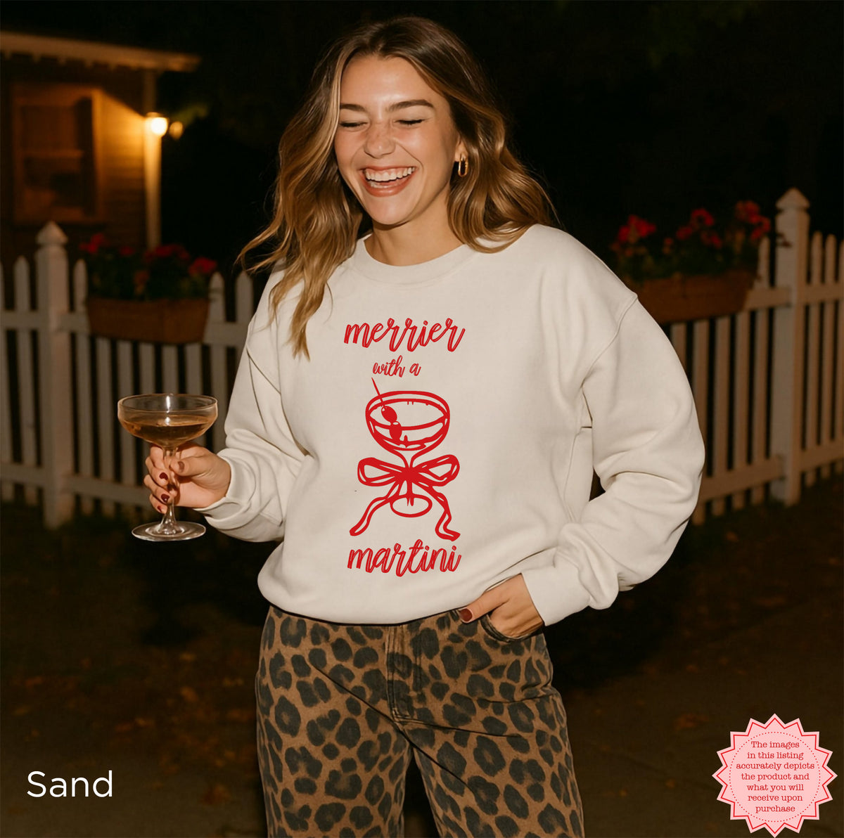 Sand-colored crewneck sweatshirt featuring the Merrier With A Martini coquette Christmas graphic, neutral holiday outfit.