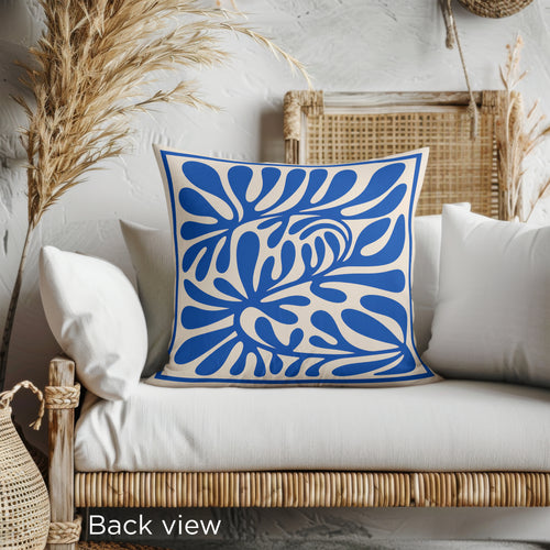 Modern Mediterranean decorative cushion with bold cobalt blue abstract leaf pattern and soft neutral background.