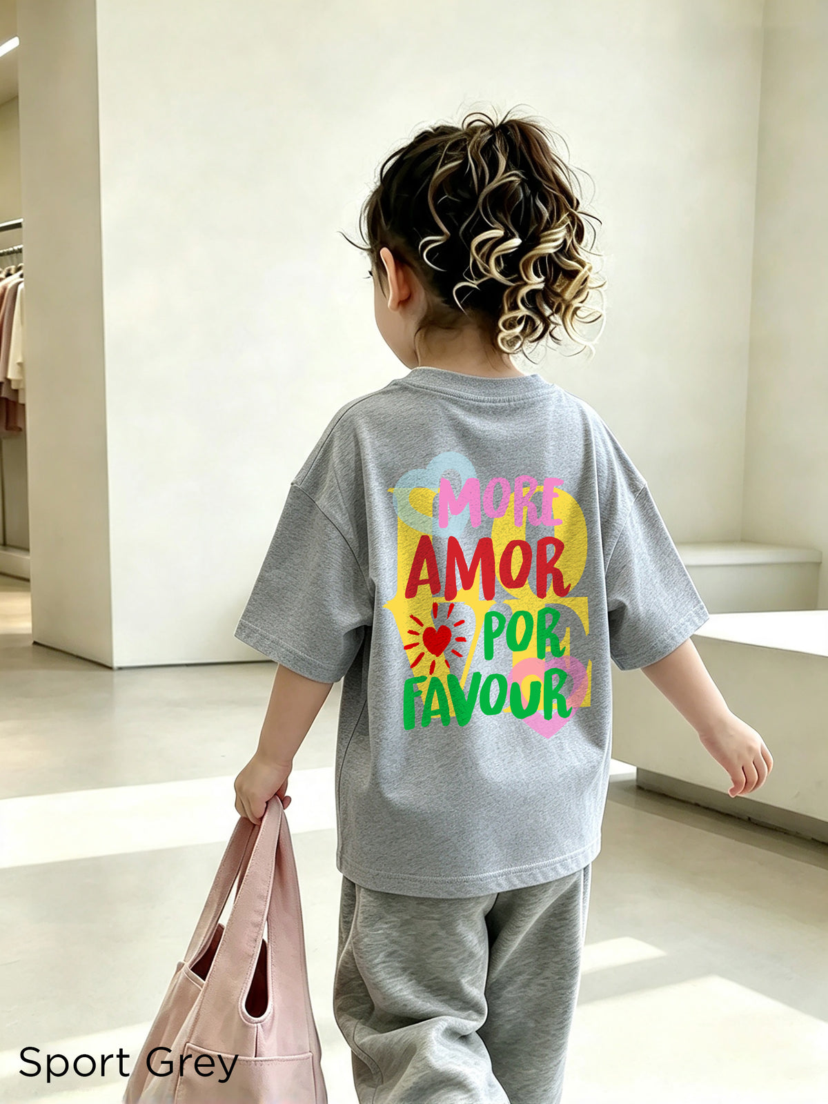Toddler wearing a Sport Grey More Amore Por Favour graphic T-shirt with a bright, colourful back print.