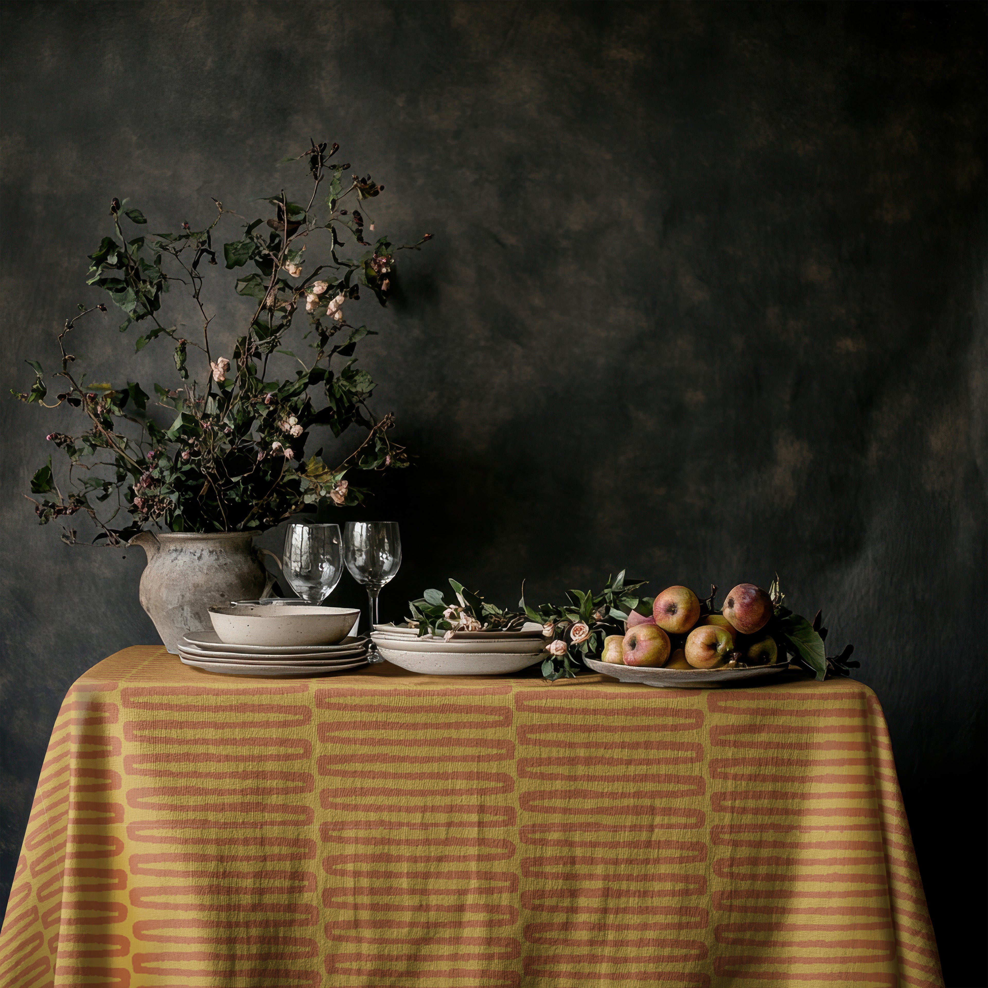 Square mustard tablecloth styled with woven placemats and neutral ceramic dinnerware