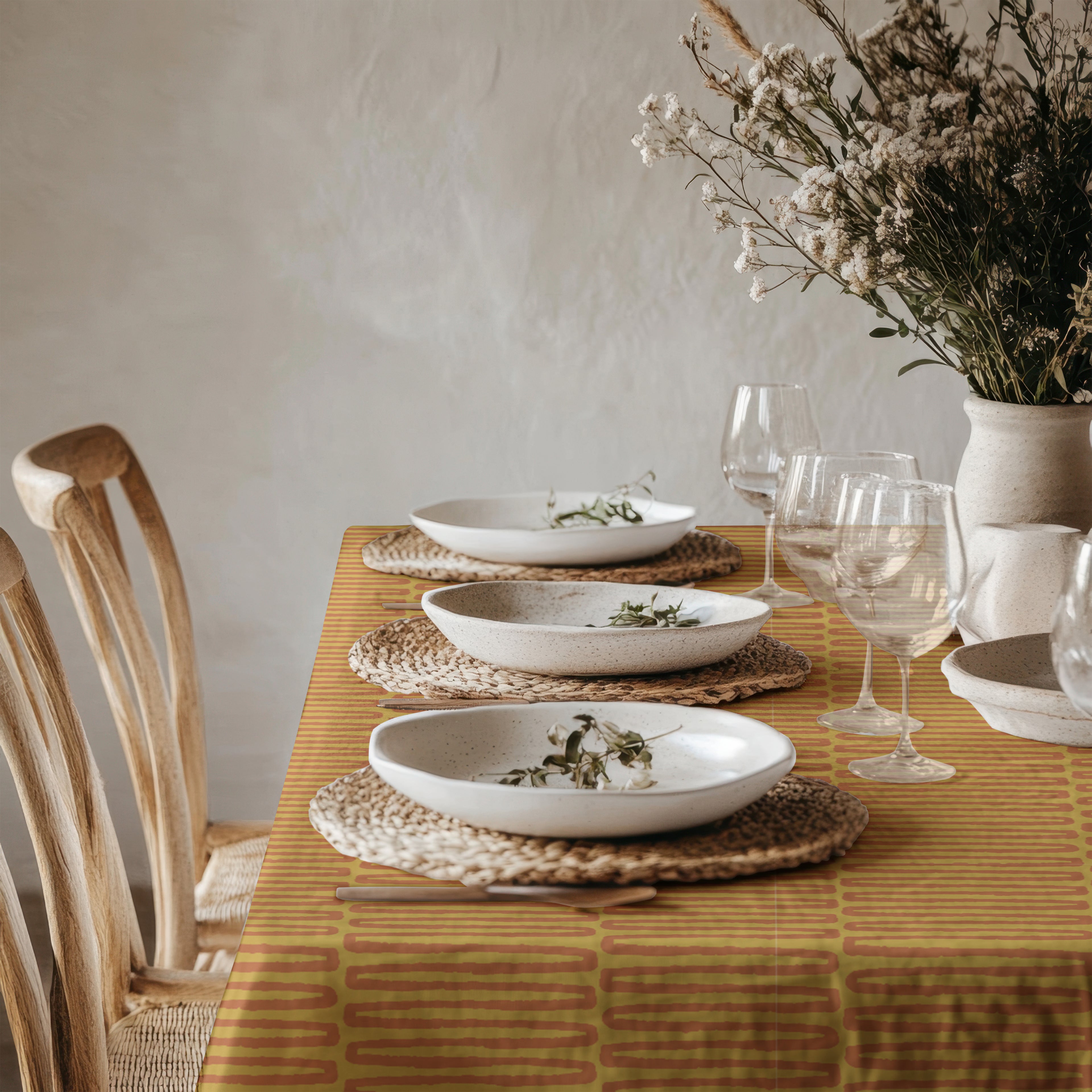 Mediterranean inspired mustard tablecloth displayed in moody dining room with ceramic table setting