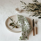 Hand drawn olive branch cotton twill cloth napkin displayed on elegant dining table with botanical home decor