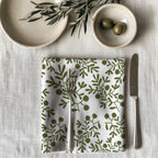 Single olive branch dinner napkin folded on table showcasing one-sided botanical print and premium reusable cotton fabric