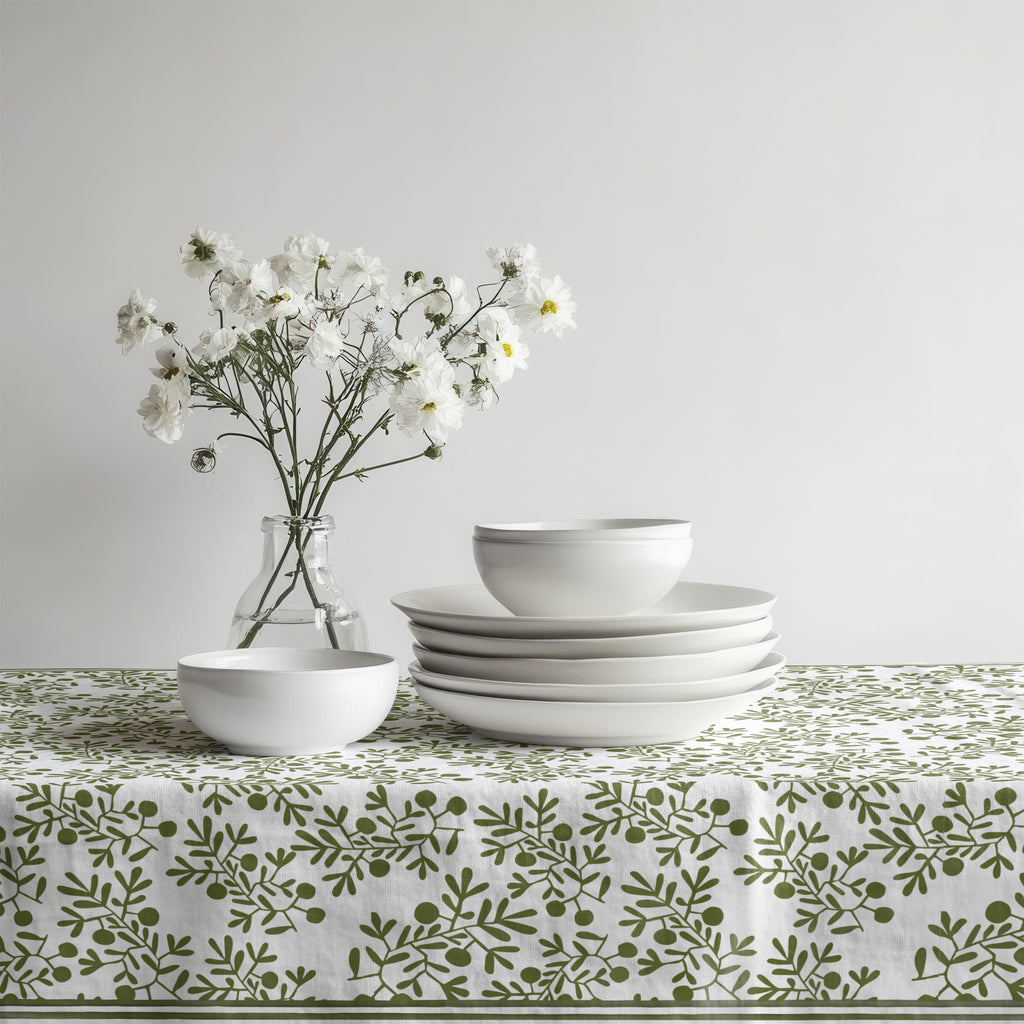 Green olive pattern tablecloth paired with ceramic dinnerware and natural woven placemats.