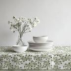Green olive pattern tablecloth paired with ceramic dinnerware and natural woven placemats.