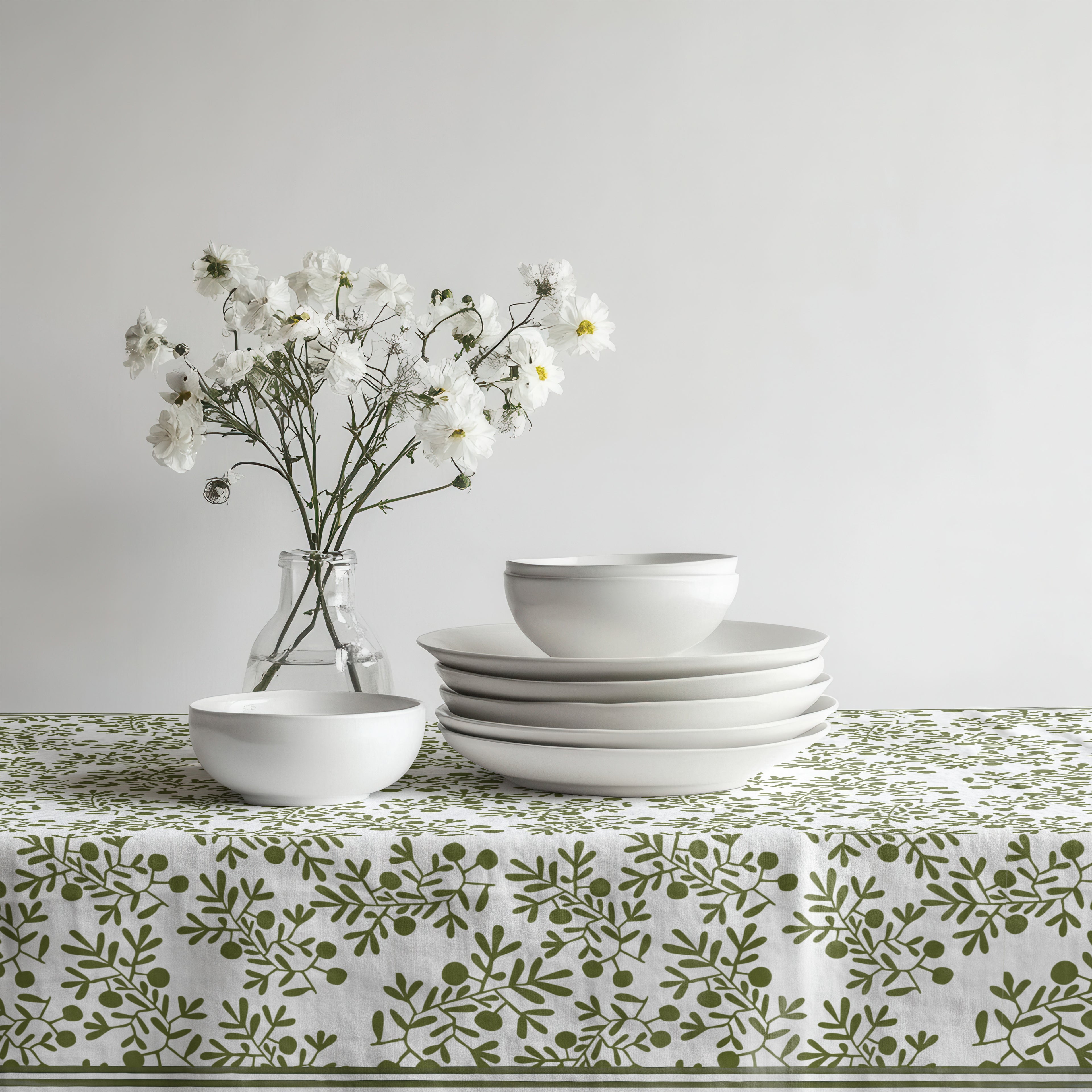 Green olive pattern tablecloth paired with ceramic dinnerware and natural woven placemats.