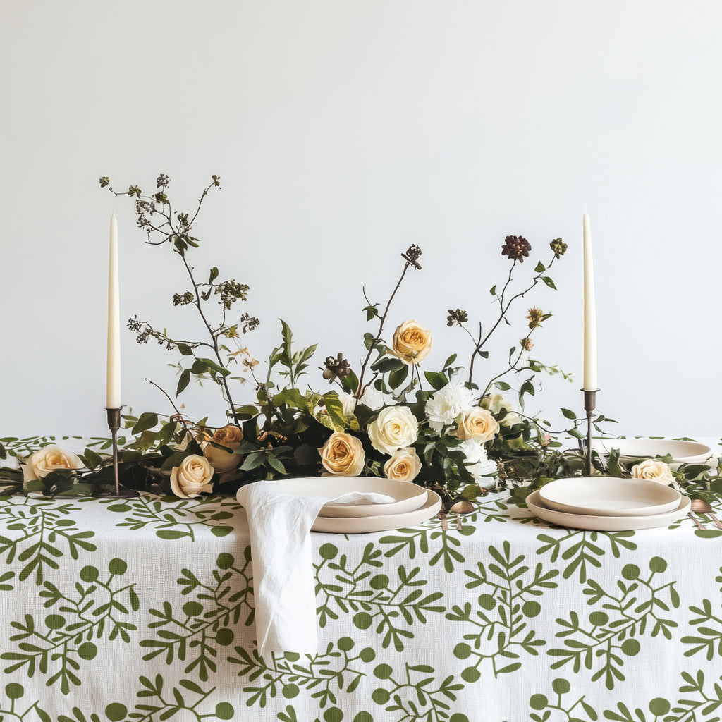 Hand-drawn olive pattern cotton tablecloth featuring green botanical motifs on a white background, styled for elegant Mediterranean entertaining.