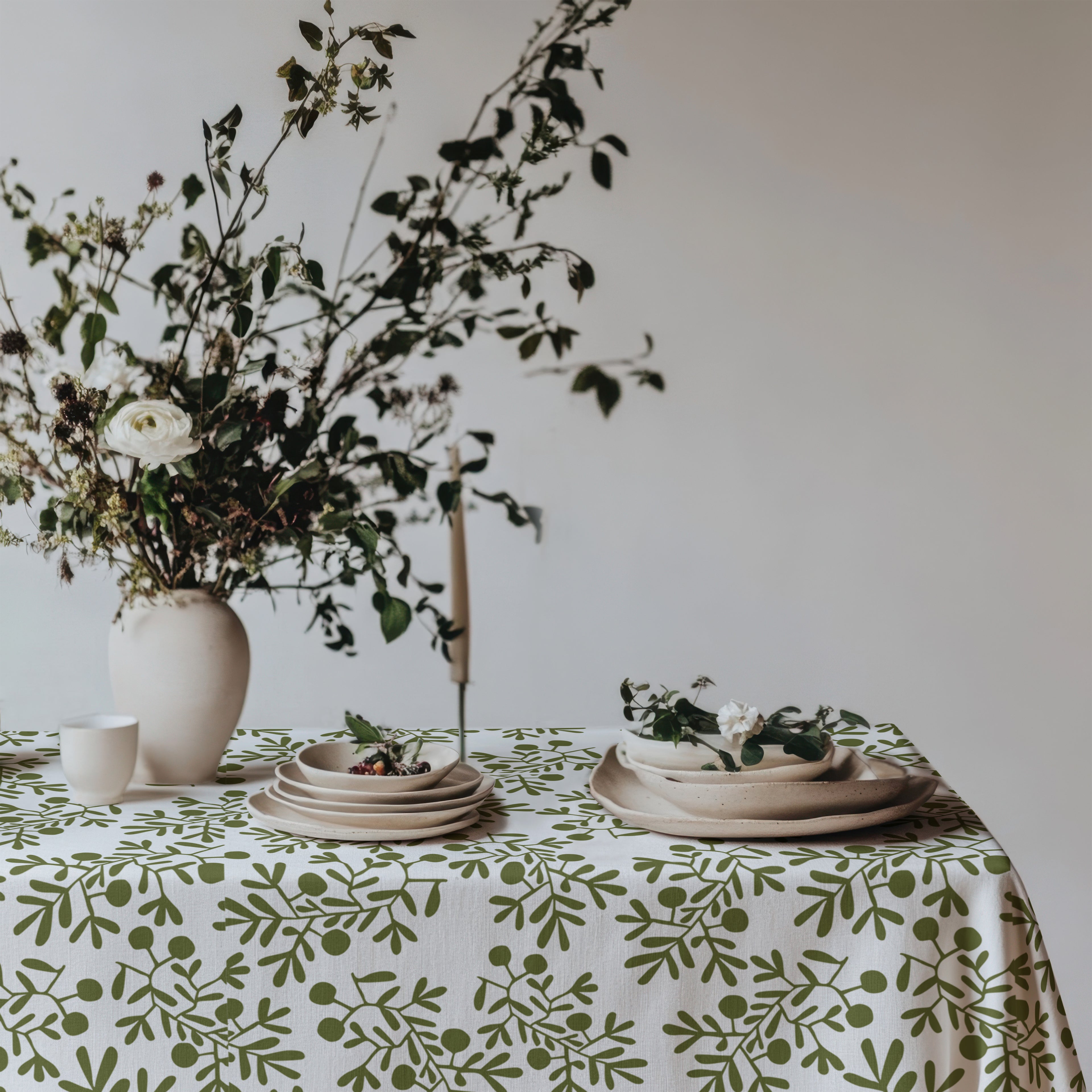 Mediterranean-inspired dining table featuring botanical olive tablecloth and neutral home décor.