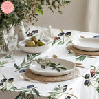 Olive branch design tablecloth laid on a dark-toned table, creating a cozy Mediterranean dining setting.