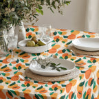 Colorful orange grove tablecloth featuring vibrant citrus fruit and green leaves on premium cotton twill fabric.