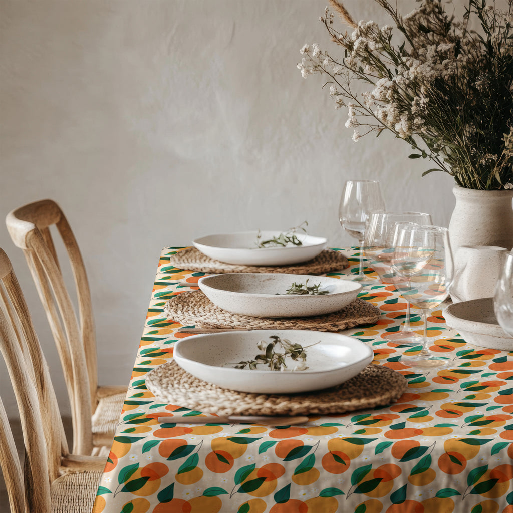 Mediterranean citrus tablecloth styled with ceramic dinnerware and fresh greenery in a bright modern dining room.