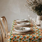 Mediterranean citrus tablecloth styled with ceramic dinnerware and fresh greenery in a bright modern dining room.