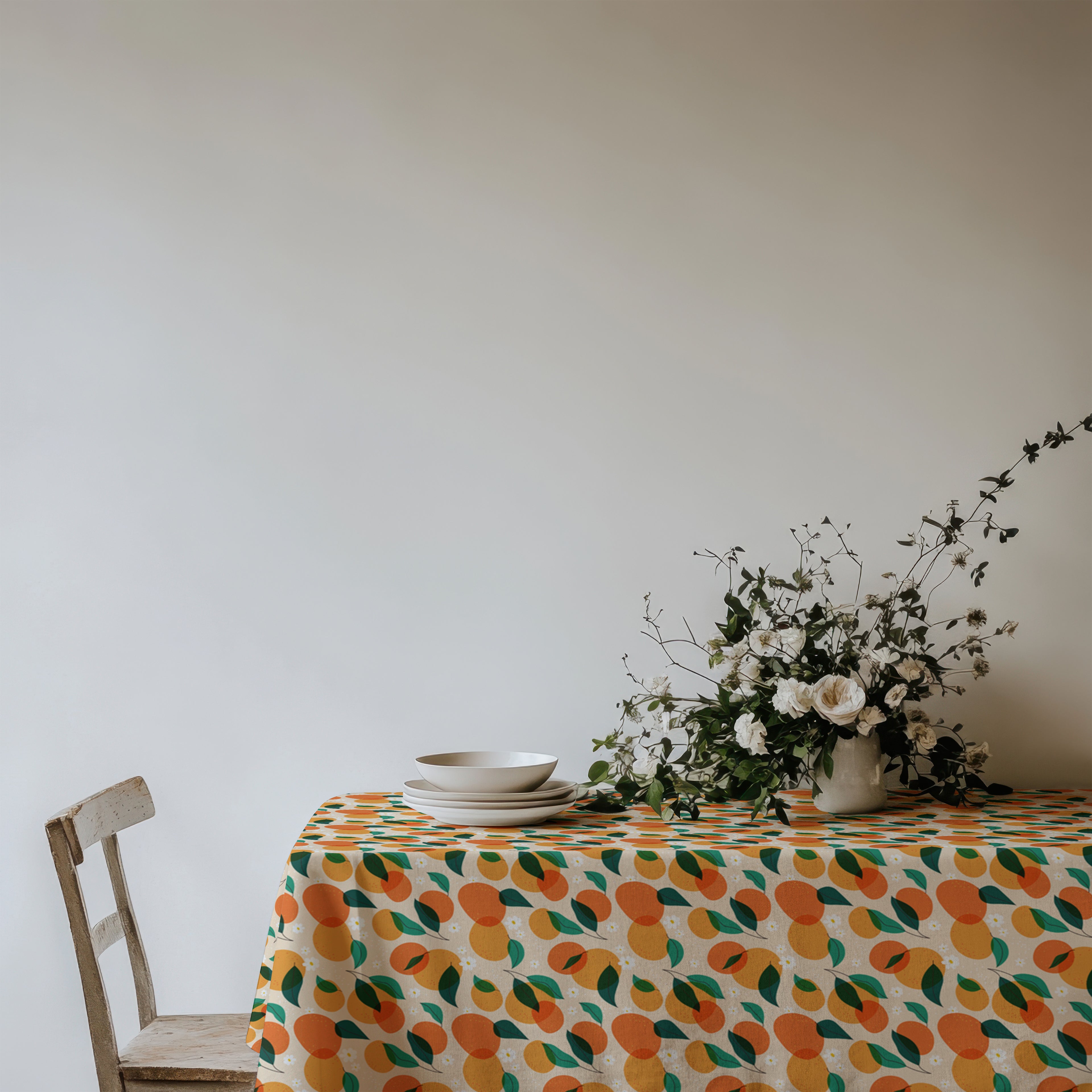 Summer oranges tablecloth creating a cheerful Mediterranean tablescape with white plates and natural décor.