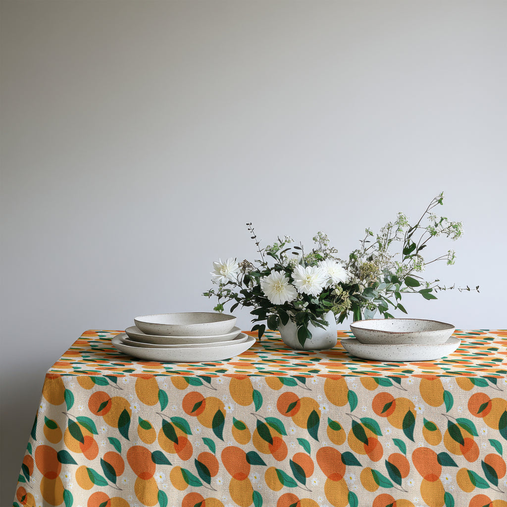 Vibrant orange grove tablecloth adding color and warmth to a coastal-inspired dining room setting.