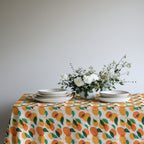 Vibrant orange grove tablecloth adding color and warmth to a coastal-inspired dining room setting.