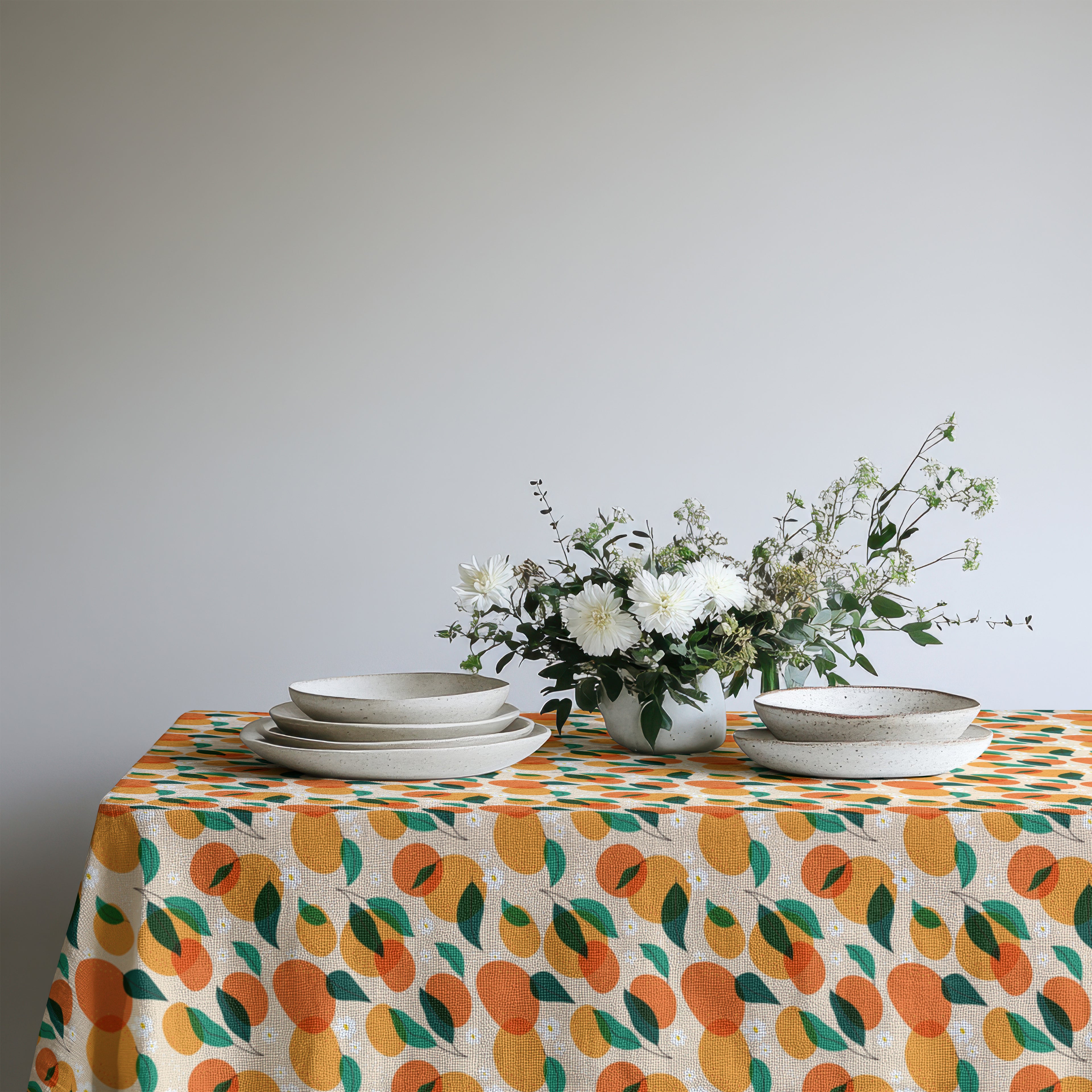 Vibrant orange grove tablecloth adding color and warmth to a coastal-inspired dining room setting.