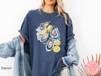 Denim blue Comfort Colors T-shirt with watercolor oyster design and lemons, styled for fisherman aesthetic and seaside casual wear.